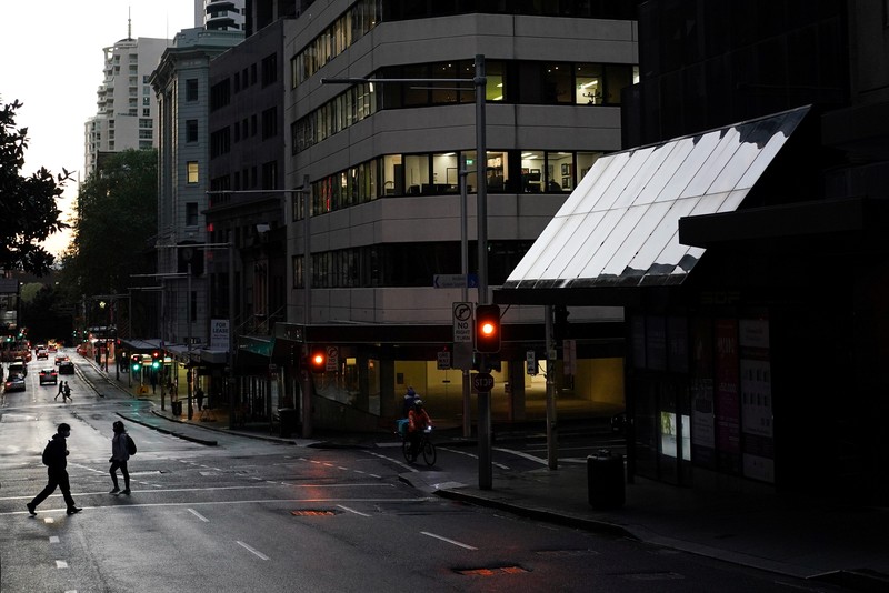 HEALTH-CORONAVIRUS/AUSTRALIA A pedestrian crosses a street at sunset in the city centre during a lockdown to curb the spread of a coronavirus disease (COVID-19) outbreak in Sydney, Australia, September 14, 2021. REUTERS/Loren Elliott TPX IMAGES OF THE DAY