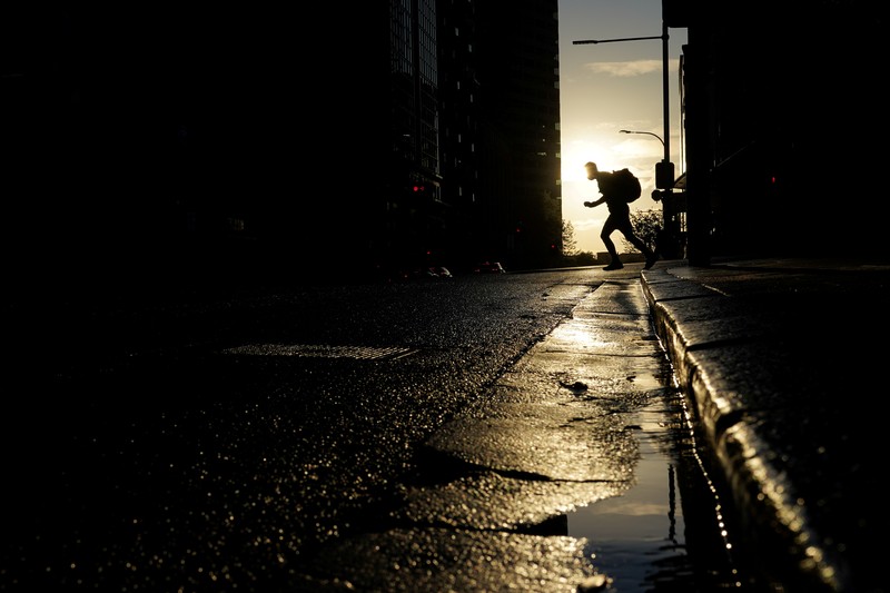 HEALTH-CORONAVIRUS/AUSTRALIA A pedestrian crosses a street at sunset in the city centre during a lockdown to curb the spread of a coronavirus disease (COVID-19) outbreak in Sydney, Australia, September 14, 2021. REUTERS/Loren Elliott TPX IMAGES OF THE DAY