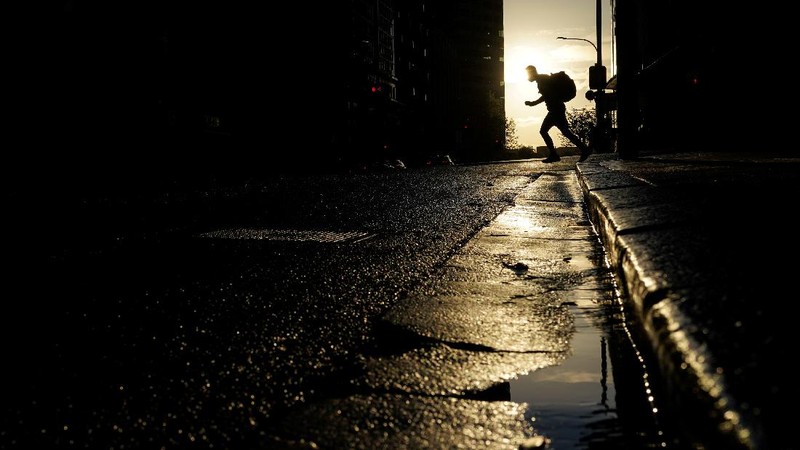 A pedestrian crosses a street at sunset in the city centre during a lockdown to curb the spread of a coronavirus disease (COVID-19) outbreak in Sydney, Australia, September 14, 2021.  REUTERS/Loren Elliott     TPX IMAGES OF THE DAY