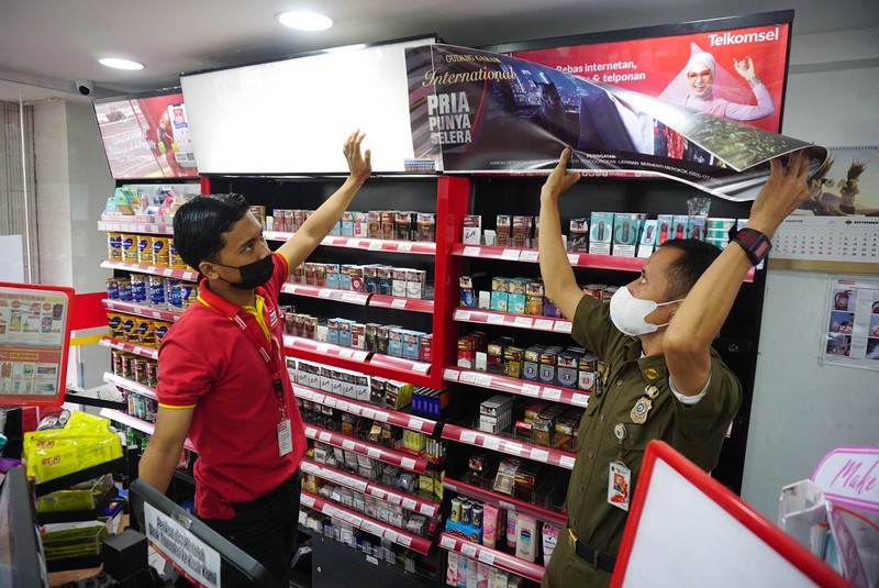 Petugas Satpol PP Jakarta Barat menutup gerai minimarket yang menjual rokok di Alfamart, Jakarta Barat, Selasa (14/9/2021). (CNBC Indonesia/Tri Susilo)