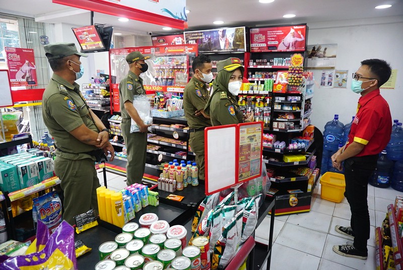 Petugas Satpol PP Jakarta Barat menutup gerai minimarket yang menjual rokok di Alfamart, Jakarta Barat, Selasa (14/9/2021). (CNBC Indonesia/Tri Susilo)