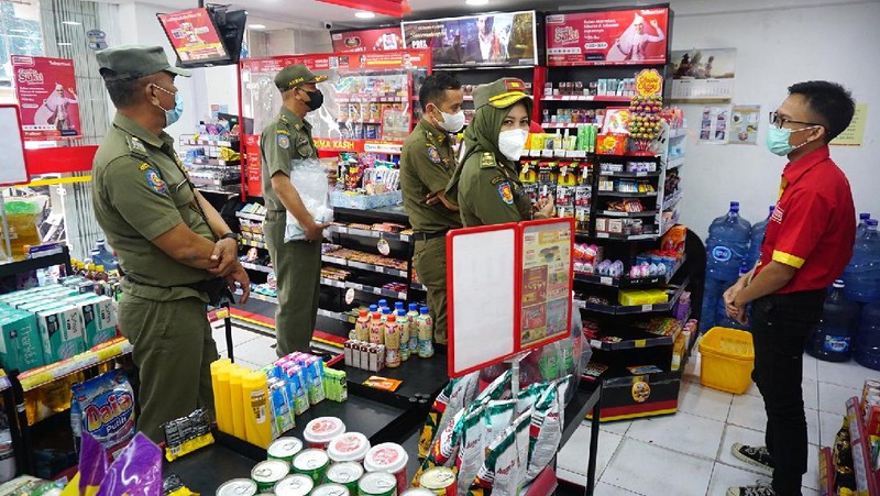 Petugas Satpol PP Jakarta Barat menutup gerai minimarket yang menjual rokok di Alfamart, Jakarta Barat, Selasa (14/9/2021). (CNBC Indonesia/Tri Susilo)