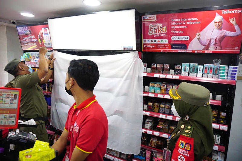 Petugas Satpol PP Jakarta Barat menutup gerai minimarket yang menjual rokok di Alfamart, Jakarta Barat, Selasa (14/9/2021). (CNBC Indonesia/Tri Susilo)