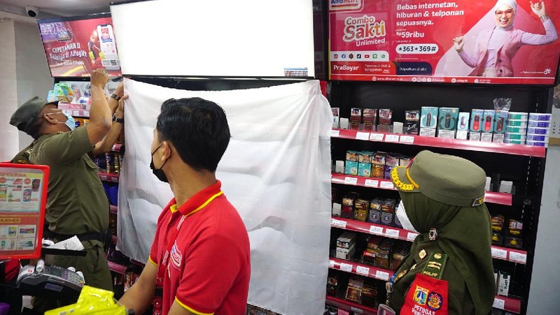 Petugas Satpol PP Jakarta Barat menutup gerai minimarket yang menjual rokok di Alfamart, Jakarta Barat, Selasa (14/9/2021). (CNBC Indonesia/Tri Susilo)