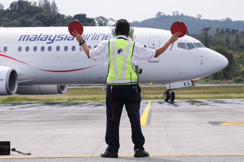 HEALTH-CORONAVIRUS/MALAYSIA-TOURISM A Malaysia Airlines crew member directs the first batch of tourists upon their arrival at the airport as Langkawi reopen to domestic tourists, amid the coronavirus disease (COVID-19) pandemic in Malaysia September 16, 2021. REUTERS/Lim Huey Teng