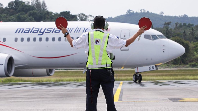 A Malaysia Airlines crew member directs the first batch of tourists upon their arrival at the airport as Langkawi reopen to domestic tourists, amid the coronavirus disease (COVID-19) pandemic in Malaysia September 16, 2021. REUTERS/Lim Huey Teng
