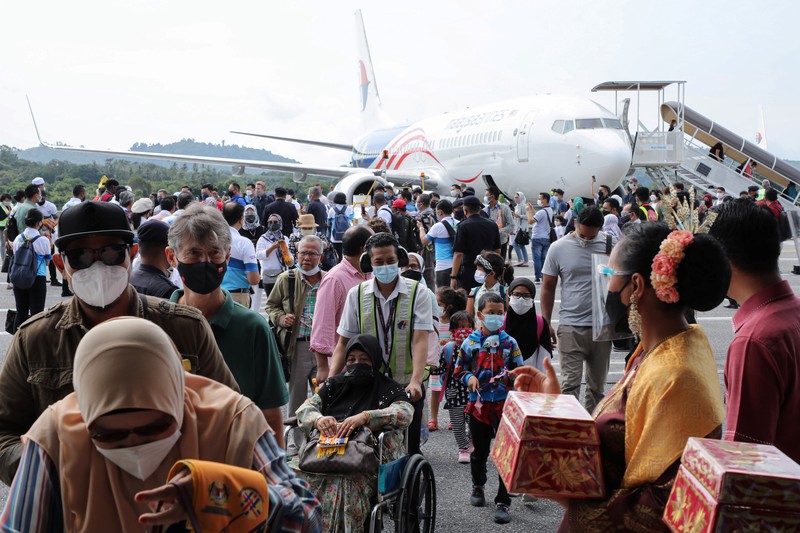 HEALTH-CORONAVIRUS/MALAYSIA-TOURISM A Malaysia Airlines crew member directs the first batch of tourists upon their arrival at the airport as Langkawi reopen to domestic tourists, amid the coronavirus disease (COVID-19) pandemic in Malaysia September 16, 2021. REUTERS/Lim Huey Teng
