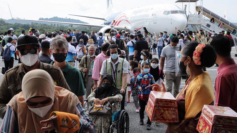 A Malaysia Airlines crew member directs the first batch of tourists upon their arrival at the airport as Langkawi reopen to domestic tourists, amid the coronavirus disease (COVID-19) pandemic in Malaysia September 16, 2021. REUTERS/Lim Huey Teng