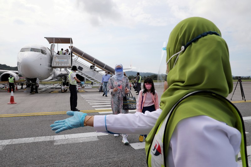 HEALTH-CORONAVIRUS/MALAYSIA-TOURISM A Malaysia Airlines crew member directs the first batch of tourists upon their arrival at the airport as Langkawi reopen to domestic tourists, amid the coronavirus disease (COVID-19) pandemic in Malaysia September 16, 2021. REUTERS/Lim Huey Teng