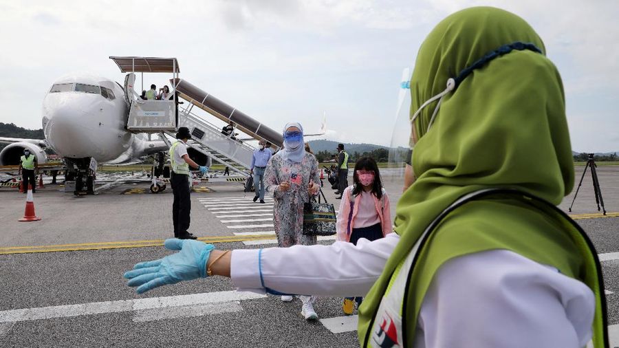 A Malaysia Airlines crew member directs the first batch of tourists upon their arrival at the airport as Langkawi reopen to domestic tourists, amid the coronavirus disease (COVID-19) pandemic in Malaysia September 16, 2021. REUTERS/Lim Huey Teng