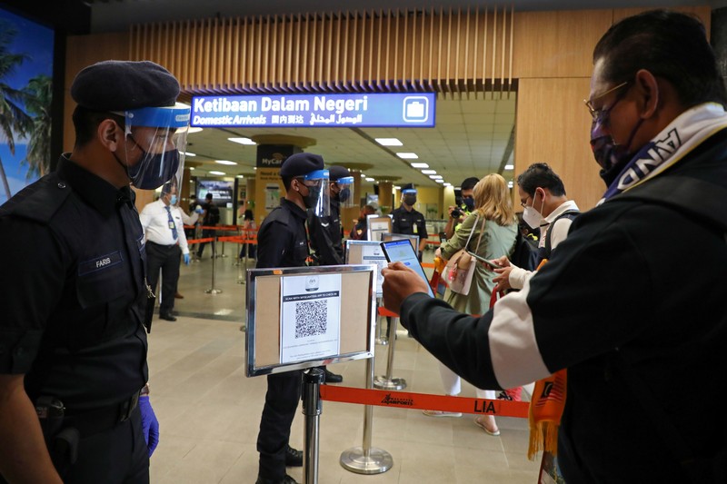 HEALTH-CORONAVIRUS/MALAYSIA-TOURISM A Malaysia Airlines crew member directs the first batch of tourists upon their arrival at the airport as Langkawi reopen to domestic tourists, amid the coronavirus disease (COVID-19) pandemic in Malaysia September 16, 2021. REUTERS/Lim Huey Teng