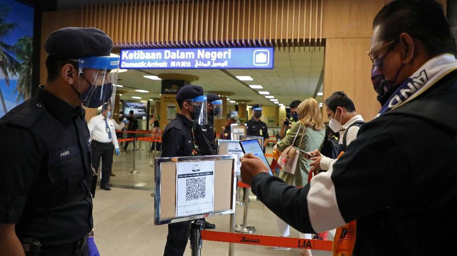 A tourist scans a QR code to check in upon arriving at the airport as Langkawi reopens to domestic tourists, amid the coronavirus disease (COVID-19) pandemic in Malaysia September 16, 2021. REUTERS/Lim Huey Teng