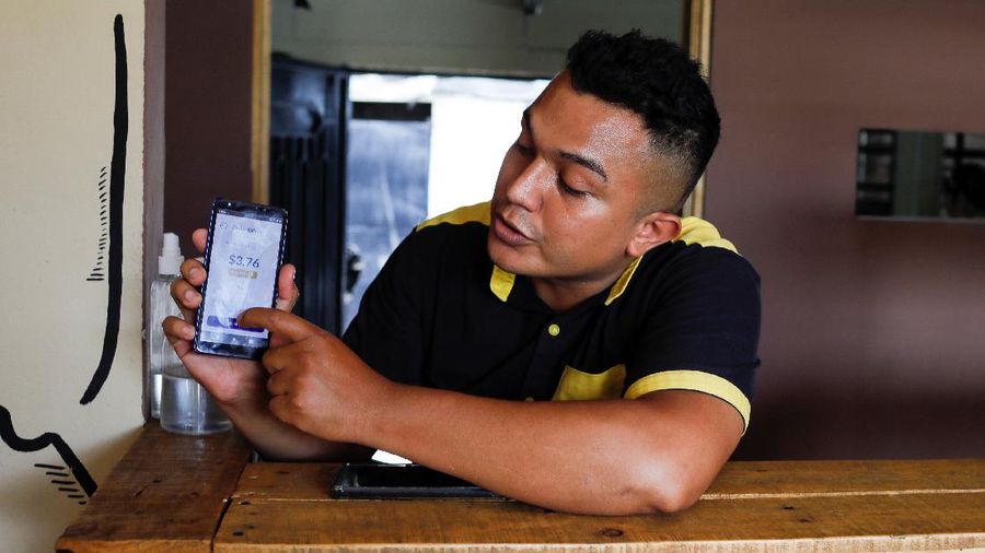 Alejandro Martinez, owner of Perronas Pizzas, helps a customer to pay for her order with Chivo Wallet, a Bitcoin wallet that the Salvadoran government is launching for the use of Bitcoin as a legal tender, in Apopa, El Salvador, September 9, 2021. REUTERS/Jose Cabezas