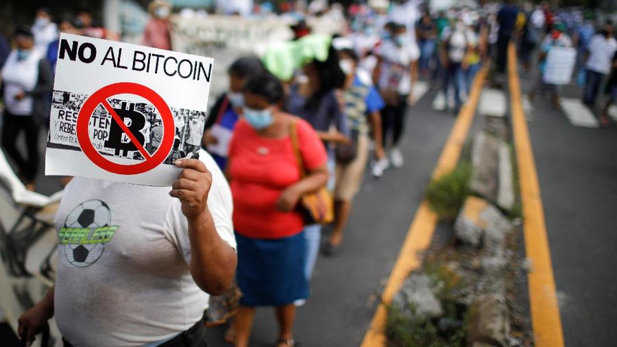 People take part in a protest against the use of Bitcoin as legal tender and legal reforms to extend president Nayib Bukele's term in San Salvador, El Salvador, September 15, 2021. The placard reads: 