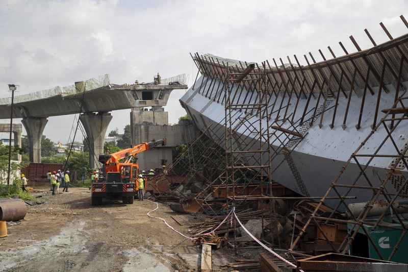 India Bridge Collapse Workers stand near an under-construction bridge that collapsed in Mumbai, India, Friday, Sept. 17, 2021. According to police more than a dozen people were injured after a part of the under-construction bridge collapsed early Friday morning in Mumbai. (AP Photo/Rafiq Maqbool)