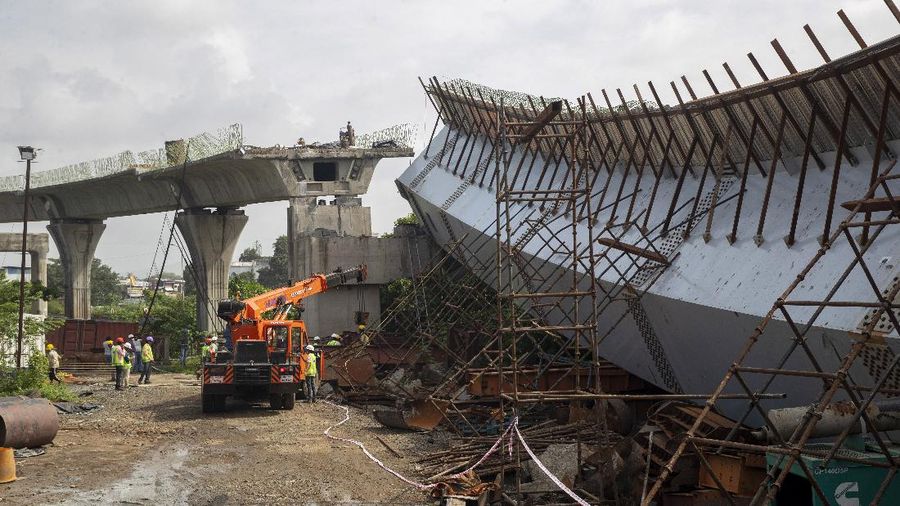 Workers stand near an under-construction bridge that collapsed in Mumbai, India, Friday, Sept. 17, 2021. According to police more than a dozen people were injured after a part of the under-construction bridge collapsed early Friday morning in Mumbai. (AP Photo/Rafiq Maqbool)