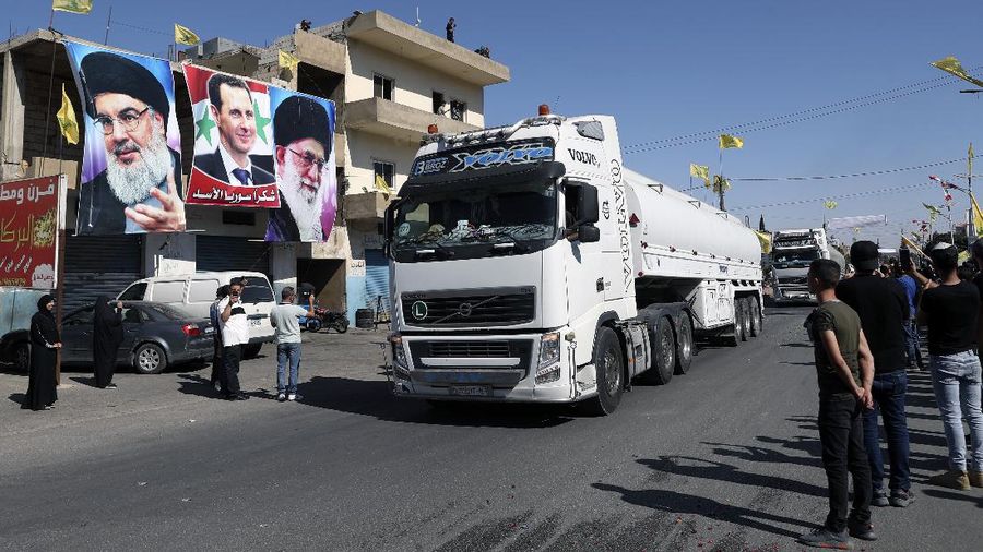 Hezbollah supporter celebrate as a convoy of tanker trucks carrying Iranian diesel crossed the border from Syria into Lebanon, arrives at the eastern town of el-Ain, Lebanon, Thursday, Sept. 16, 2021. The delivery violates U.S. sanctions imposed on Tehran after former President Donald Trump pulled America out of a nuclear deal between Iran and world powers three years ago. The poster of Hezbollah leader Sayyed Hassan Nasrallah, left, Syrian President Bashar Assad, center, and the Iranian Supreme Leader Ayatollah Ali Khamenei, right. (AP Photo/Bilal Hussein)