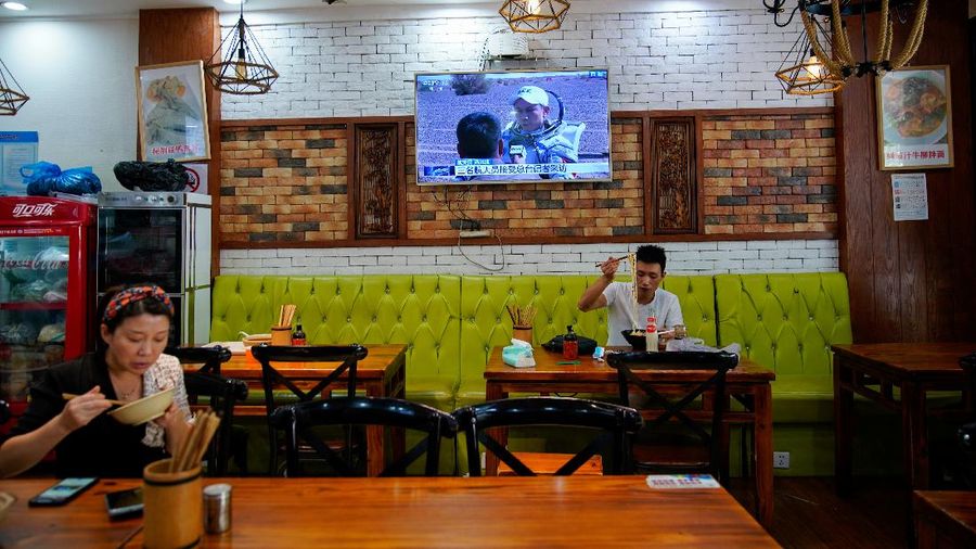 A television shows news footage of three Chinese astronauts, the first sent to orbit for space station construction, who returned to Earth safely today after completing a 90-day visit to the unfinished space station, at a restaurant in Shanghai, China September 17, 2021. REUTERS/Aly Song