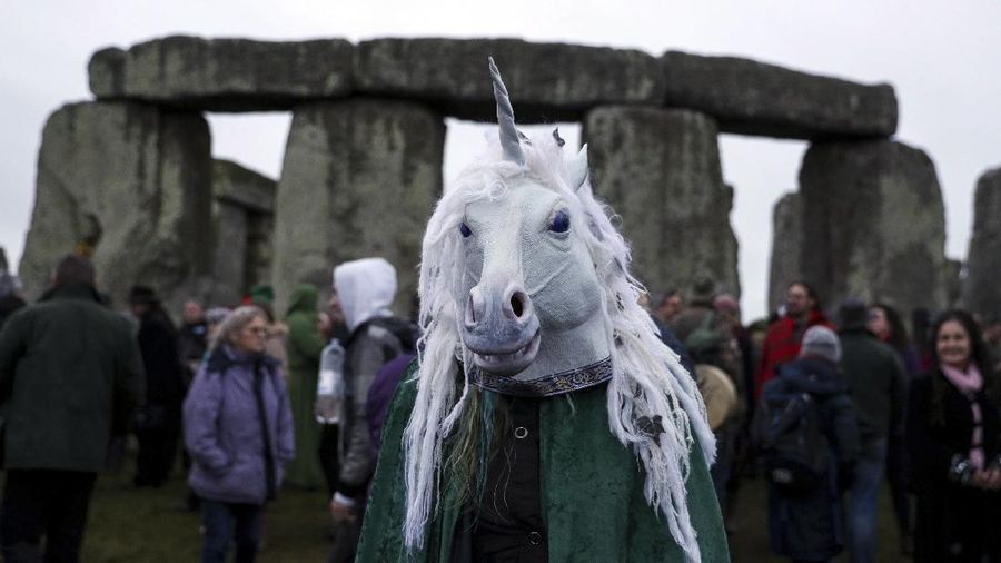 A person wears a costume as people gather at Stonehenge in Wiltshire, western England, on the winter solstice to witness the sunrise after the longest night of the year Friday Dec. 22, 2017. (Andrew Matthews/PA via AP)