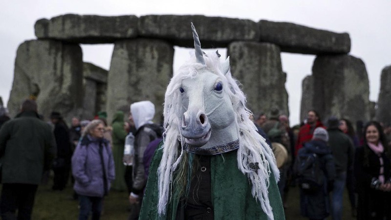 A person wears a costume as people gather at Stonehenge in Wiltshire, western England, on the winter solstice to witness the sunrise after the longest night of the year Friday Dec. 22, 2017. (Andrew Matthews/PA via AP)