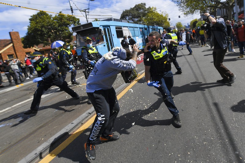 A protester is detained by Victoria police during a 
