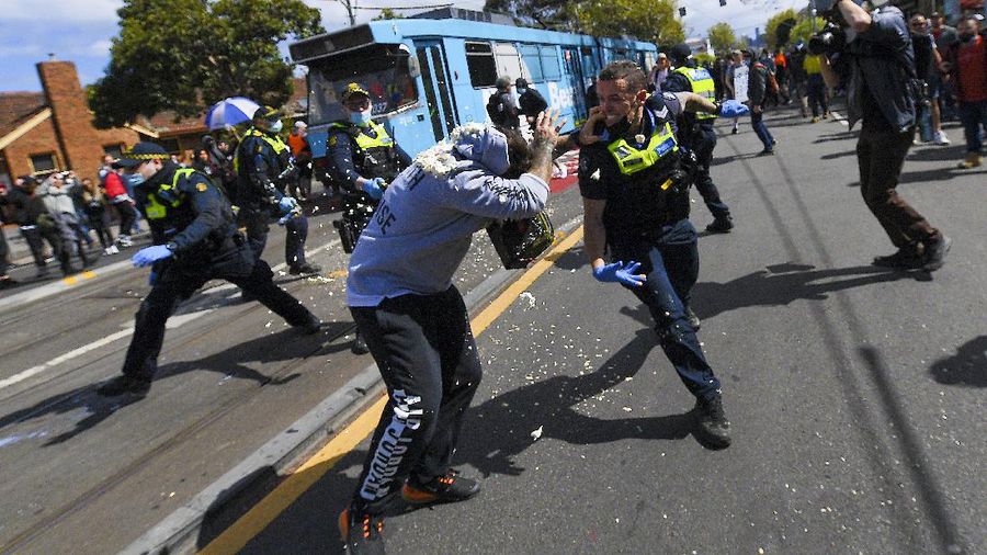 A protester is detained by Victoria police during a 