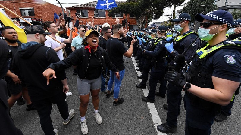 A protester is detained by Victoria police during a 