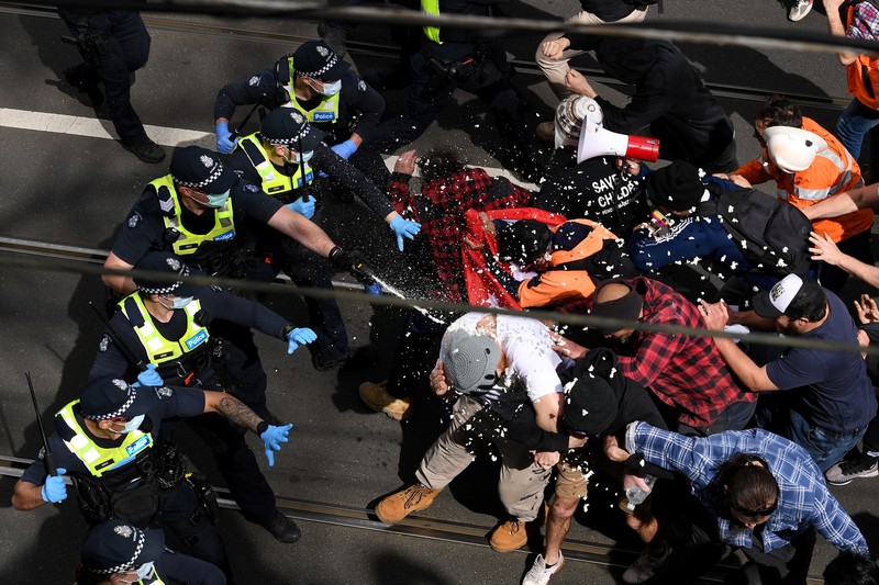 A protester is detained by Victoria police during a 