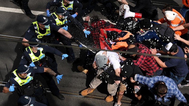 A protester is detained by Victoria police during a 