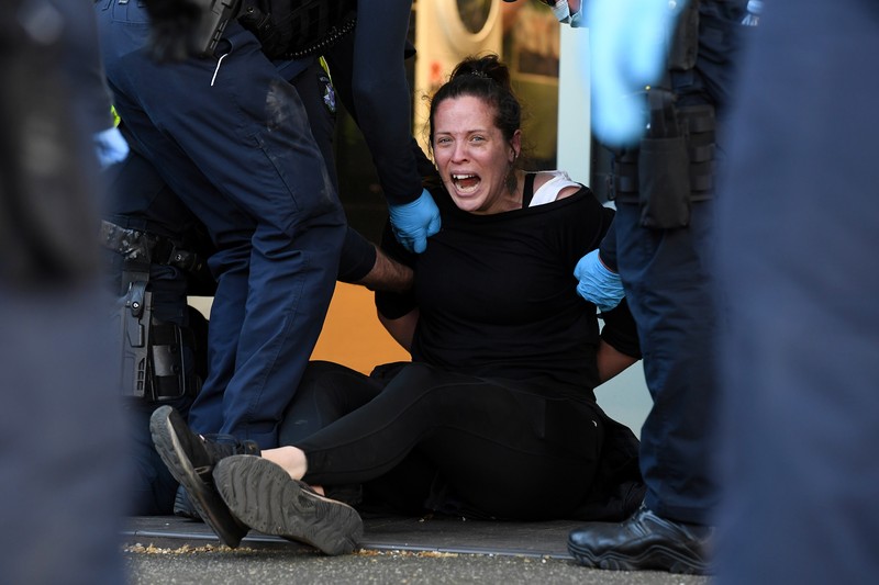 HEALTH-CORONAVIRUS/AUSTRALIA-PROTEST A protester is detained by Victoria police during a