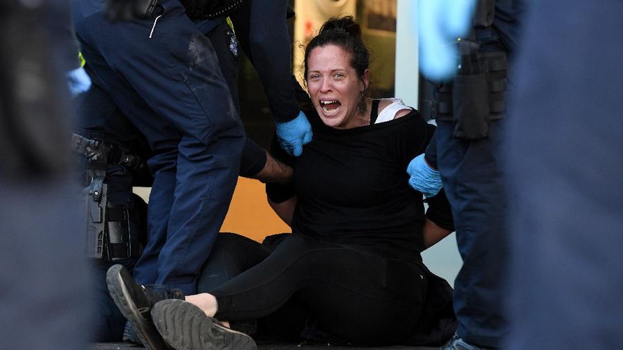 A protester is detained by Victoria police during a 