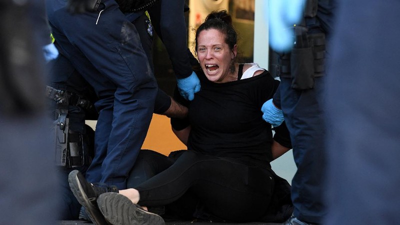 A protester is detained by Victoria police during a 