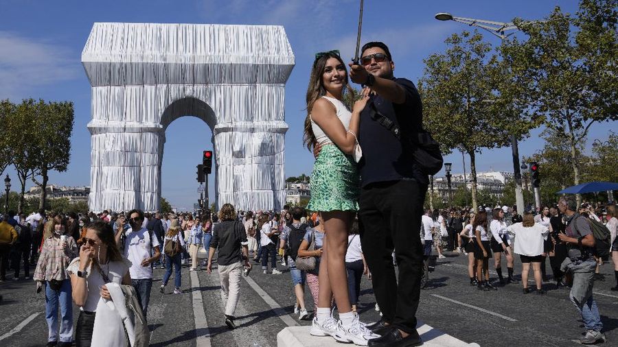 Mexican tourists pose for a selfie in front of the wrapped Arc de Triomphe monument Saturday, Sept. 18, 2021 in Paris. The 