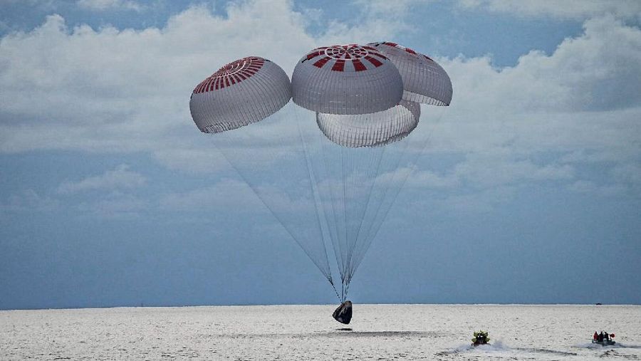 In this image taken provided by SpaceX, a capsule carrying four people parachutes into the Atlantic Ocean off the Florida coast, Saturday, Sept. 18, 2021. The all-amateur crew was the first to circle the world without a professional astronaut.  (SpaceX via AP)