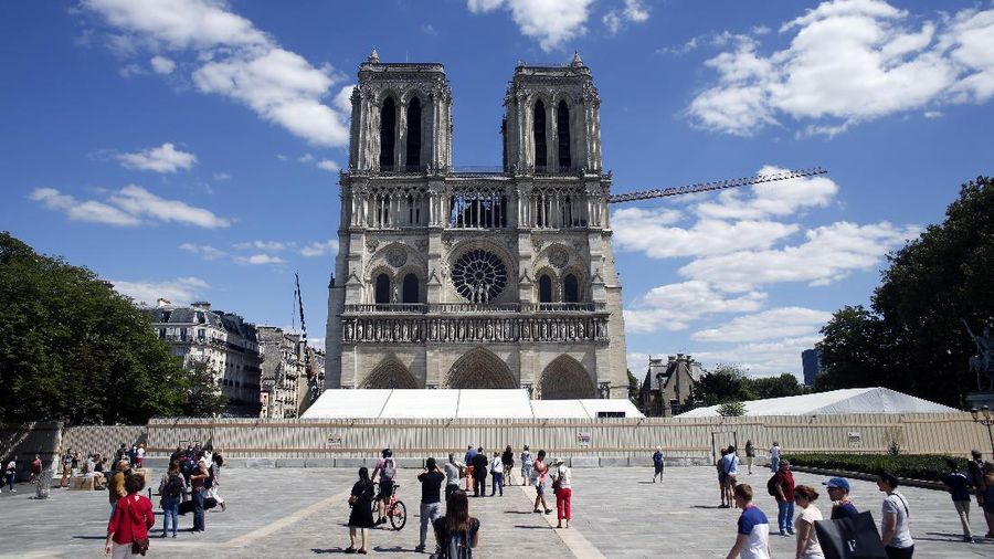 FILE - I this May 31, 2020 file photo, people walk on the forecourt of Notre Dame's Cathedral, in Paris. France's Notre Dame Cathedral is finally stable and secure enough for artisans to start rebuilding it, more than two years after the shocking fire that tore through its roof, knocked down its spire and threatened to bring the rest of the medieval monument down, too. (AP Photo/Thibault Camus, File)