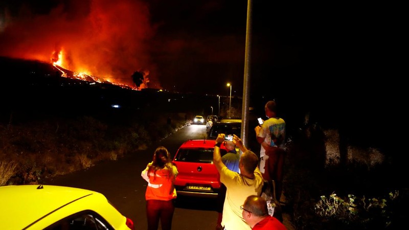 Residents watch lava following the eruption of a volcano in the Cumbre Vieja national park at El Paso, on the Canary Island of La Palma, September 19, 2021. Pictures taken September 19, 2021. REUTERS/Borja Suarez