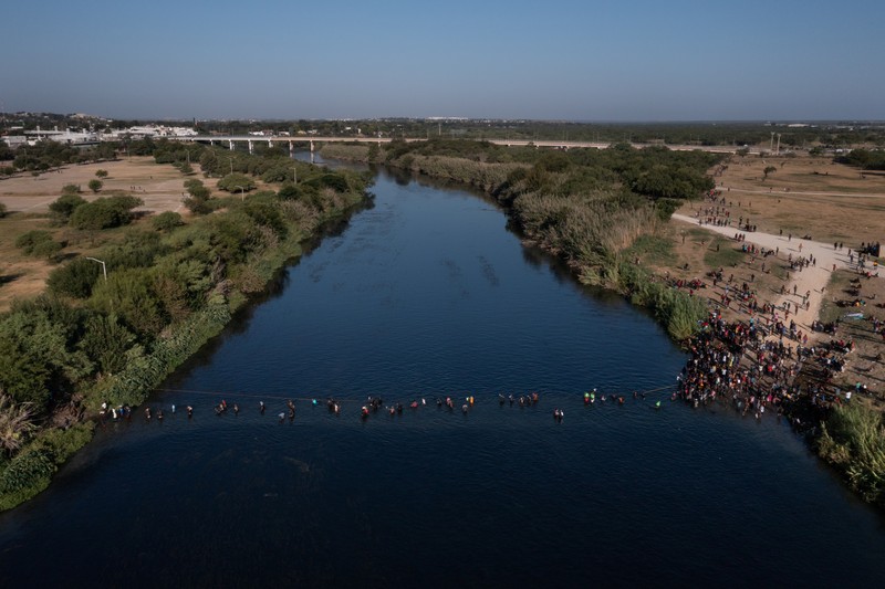 Migrants seeking refuge in the United States walk back into the Mexican side carrying their belongings inside plastic bags while crossing the Rio Bravo river which divides the border between Ciudad Acuna, Mexico and Del Rio, Texas, U.S., to avoid being deported, in Ciudad Acuna, Mexico, September 19, 2021. REUTERS/Daniel Becerril   REFILE- QUALITY REPEAT