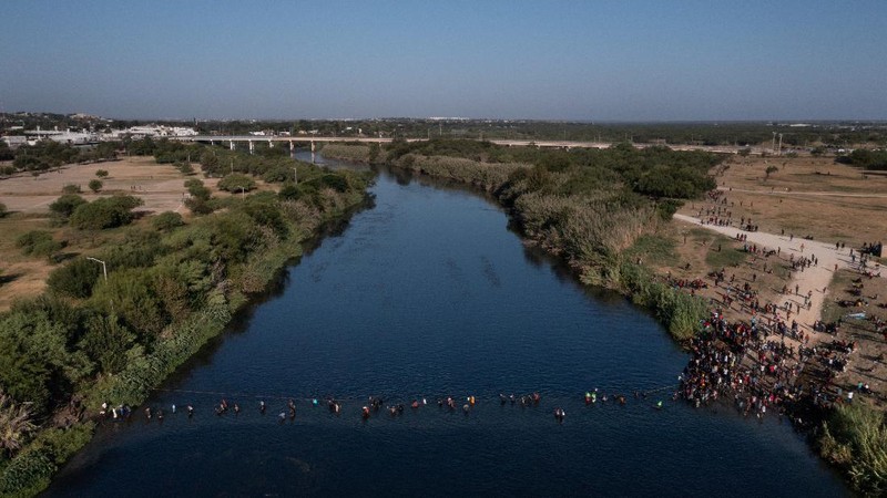 Migrants seeking refuge in the United States walk back into the Mexican side carrying their belongings inside plastic bags while crossing the Rio Bravo river which divides the border between Ciudad Acuna, Mexico and Del Rio, Texas, U.S., to avoid being deported, in Ciudad Acuna, Mexico, September 19, 2021. REUTERS/Daniel Becerril   REFILE- QUALITY REPEAT