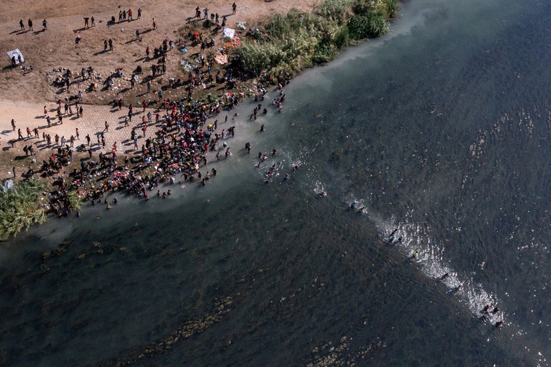 Migrants seeking refuge in the United States walk back into the Mexican side carrying their belongings inside plastic bags while crossing the Rio Bravo river which divides the border between Ciudad Acuna, Mexico and Del Rio, Texas, U.S., to avoid being deported, in Ciudad Acuna, Mexico, September 19, 2021. REUTERS/Daniel Becerril   REFILE- QUALITY REPEAT