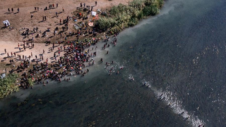Migrants seeking refuge in the United States walk back into the Mexican side carrying their belongings inside plastic bags while crossing the Rio Bravo river which divides the border between Ciudad Acuna, Mexico and Del Rio, Texas, U.S., to avoid being deported, in Ciudad Acuna, Mexico, September 19, 2021. REUTERS/Daniel Becerril   REFILE- QUALITY REPEAT