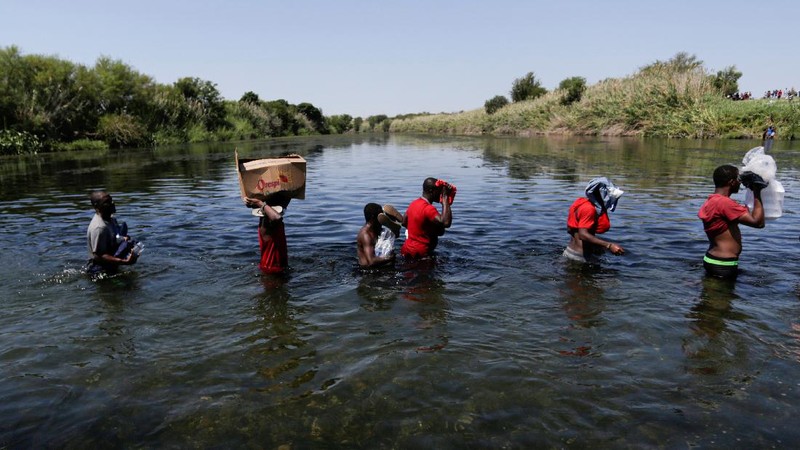 Migrants seeking refuge in the United States walk back into the Mexican side carrying their belongings inside plastic bags while crossing the Rio Bravo river which divides the border between Ciudad Acuna, Mexico and Del Rio, Texas, U.S., to avoid being deported, in Ciudad Acuna, Mexico, September 19, 2021. REUTERS/Daniel Becerril   REFILE- QUALITY REPEAT