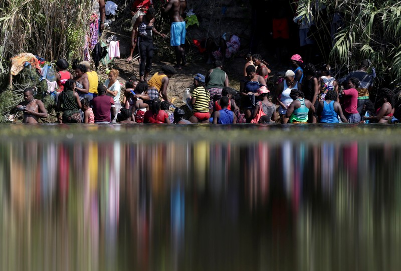 Migrants seeking refuge in the United States walk back into the Mexican side carrying their belongings inside plastic bags while crossing the Rio Bravo river which divides the border between Ciudad Acuna, Mexico and Del Rio, Texas, U.S., to avoid being deported, in Ciudad Acuna, Mexico, September 19, 2021. REUTERS/Daniel Becerril   REFILE- QUALITY REPEAT