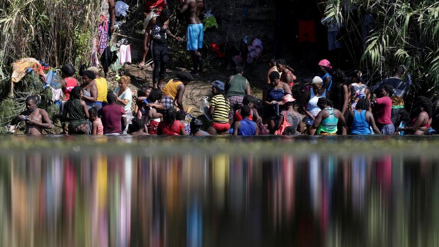 Migrants seeking refuge in the United States walk back into the Mexican side carrying their belongings inside plastic bags while crossing the Rio Bravo river which divides the border between Ciudad Acuna, Mexico and Del Rio, Texas, U.S., to avoid being deported, in Ciudad Acuna, Mexico, September 19, 2021. REUTERS/Daniel Becerril   REFILE- QUALITY REPEAT