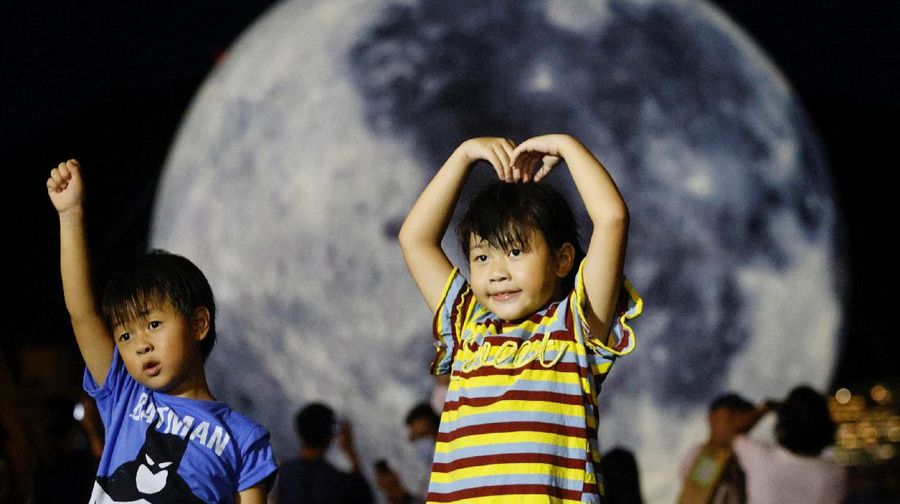 People react in front of a giant moon-shaped balloon ahead of Mid-Autumn Festival, in Hong Kong, China September 20, 2021. REUTERS/Tyrone Siu