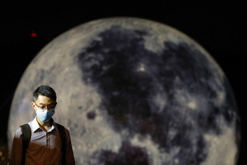 Seorang wanita berpose di depan balon raksasa berbentuk bulan menjelang Festival Pertengahan Musim Gugur, di Hong Kong, China 20 September 2021. (REUTERS/Tyrone Siu) A woman poses for a photo in front of a giant moon-shaped balloon ahead of Mid-Autumn Festival, in Hong Kong, China September 20, 2021. REUTERS/Tyrone Siu
