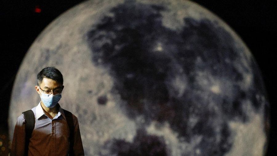 A man walks in front of a giant moon-shaped balloon ahead of Mid-Autumn Festival, in Hong Kong, China September 20, 2021. REUTERS/Tyrone Siu