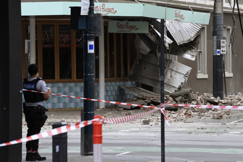 A person walks past damage to the exterior of a restaurant following an earthquake in the Windsor suburb of Melbourne, Australia, September 22, 2021.  AAP Image/James Ross via REUTERS  ATTENTION EDITORS - THIS IMAGE WAS PROVIDED BY A THIRD PARTY. NO RESALES. NO ARCHIVES. AUSTRALIA OUT. NEW ZEALAND OUT