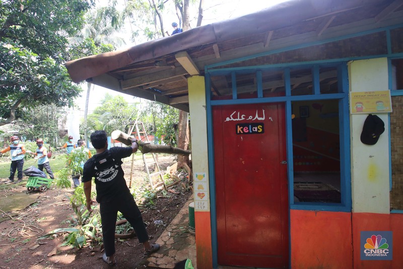 Puting beliung akibat curah hujan tinggi di Depok Sejumlah relawan dibantu para guru sekolah alam saat melakukan evakuasi pohon tumbang akibat puting beliung di Depok, Jawa Barat, Rabu 22 September 2021. Kawasan Depok dilanda hujan angin hingga hujan es di daerah Beji, Kota Depok kemarin (21/9) sore. Akibat hujan angin di Depok, pohon tumbang pun tak bisa dielakkan. Berdasarkan data Pemadam Kebakaran (Damkar), setidaknya ada enam lokasi pohon tumbang di Depok. Sejumlah relawan hingga kini mengevakuasi potongan pohon yg menimpa bagian yang rusak kanopi. Akibat kejadian tersebut proses kegiatan belajar mengajar untuk sementara diberhentikan. Salah satu guru di sekolah alam, Ode mengatakan tidak ada korban jiwa. Kerugian hanya materil dan pohon yang menimpa atap sekolah. (CNBC Indonesia/ Muhammad Sabki)