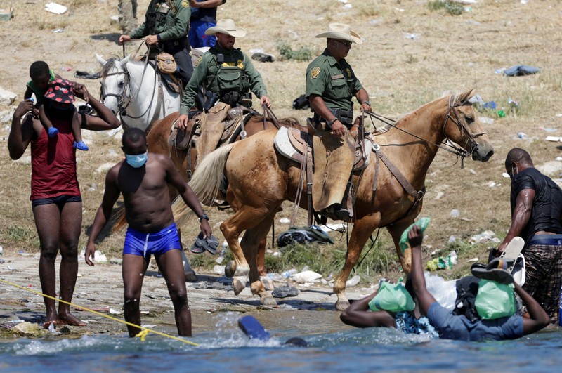 Patroli Perbatasan Amerika Serikat (AS) menggunakan kuda dalam operasi imigran ilegal Haiti U.S. Customs and Border Protection mounted officers attempt to contain migrants as they cross the Rio Grande from Ciudad Acuna, Mexico, into Del Rio, Texas, Sunday, Sept. 19, 2021. Criticism has been fueled by the images that went viral this week of Border Patrol agents on horseback using aggressive tactics against the migrants. (AP Photo/Felix Marquez)