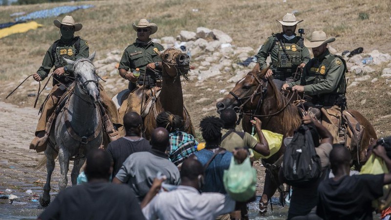 U.S. Customs and Border Protection mounted officers attempt to contain migrants as they cross the Rio Grande from Ciudad Acuna, Mexico, into Del Rio, Texas, Sunday, Sept. 19, 2021. Criticism has been fueled by the images that went viral this week of Border Patrol agents on horseback using aggressive tactics against the migrants. (AP Photo/Felix Marquez)